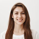 Girl is happy receive good feedback about her site. Portrait of attractive caucasian woman in white shirt smiling broadly, looking with satisfied expression at camera, feeling great after day in spa. Emotions concept